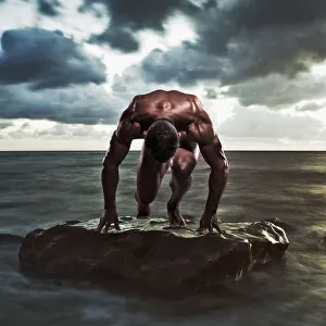 A muscular man in the starting position on a wet rock in the water;Tarifa cadiz andalusia A muscular man in the starting position on a wet rock in the water;Tarifa cadiz andalusia