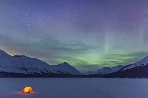Nighttime View Of A Lit Tent On A Snow Covered Trail Lake With The Moon, Stars, And Nighttime View Of A Lit Tent On A Snow Covered Trail Lake With The Moon, Stars, And
