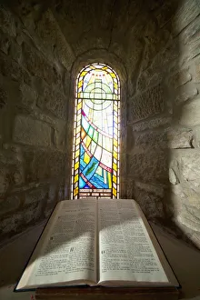 An Open Bible And A Stained Glass Window In St. Mary's Church; Holystone, Northumberland, England An Open Bible And A Stained Glass Window In St. Mary's Church; Holystone, Northumberland, England