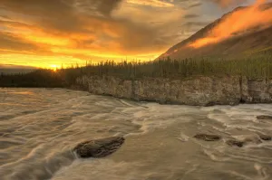 Orange Sunset On Sluice Box Rapids Above Virginia Falls, Nahanni National Park, Northwest Territories Orange Sunset On Sluice Box Rapids Above Virginia Falls, Nahanni National Park, Northwest Territories
