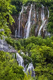 People on a footbridge crossing the large waterfall at Plitvice Lakes National Park in Lika-Senj county in Croatia People on a footbridge crossing the large waterfall at Plitvice Lakes National Park in Lika-Senj county in Croatia