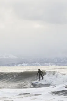 Person Surfing In Winter In Homer, Kenai Peninsula, Kachemak Bay, Alaska Person Surfing In Winter In Homer, Kenai Peninsula, Kachemak Bay, Alaska