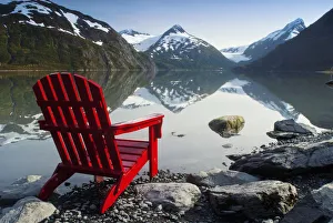 Red Adirondack Chair At Portage Lake With Chugach Mountains In The Background, Southcentral, Alaska Red Adirondack Chair At Portage Lake With Chugach Mountains In The Background, Southcentral, Alaska
