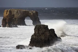 Rock formations and a natural arch in the ocean with splashing waves;South Shields Tyne Rock formations and a natural arch in the ocean with splashing waves;South Shields Tyne