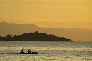 Silhouette Of Fishermen In Dugout Canoe Leaving Cape Maclear In The Evening, Lake Silhouette Of Fishermen In Dugout Canoe Leaving Cape Maclear In The Evening, Lake