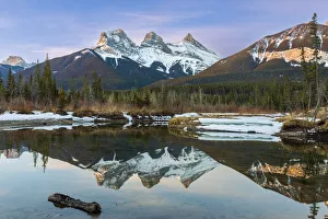 Three Sisters snow-capped mountain peaks reflected in a mirror image in a lake in Alberta, Canada; Canmore, Alberta Three Sisters snow-capped mountain peaks reflected in a mirror image in a lake in Alberta, Canada; Canmore, Alberta