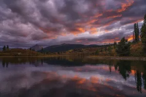 Sunset lights the clouds ablaze with colour over Rose Lake in the Yukon; Yukon, Canada Sunset lights the clouds ablaze with colour over Rose Lake in the Yukon; Yukon, Canada