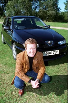 Actor Jonathan Watson September 1997 after testing ALFA ROMEO 145 kneeling in front of Actor Jonathan Watson September 1997 after testing ALFA ROMEO 145 kneeling in front of