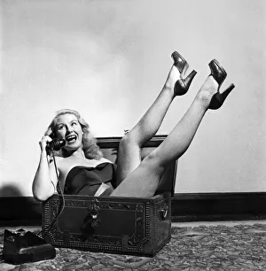 Actress June Cochrane sitting in a chest talking on the telephone. October 1952 C5181 Actress June Cochrane sitting in a chest talking on the telephone. October 1952 C5181