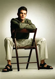 Adam Sinclair actor sitting on chair January 1999 wearing green jumper cream trousers Adam Sinclair actor sitting on chair January 1999 wearing green jumper cream trousers