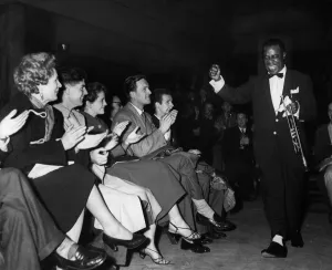 American jazz musician Louis Armstrong acknowledges the cheers of the fans as he enters American jazz musician Louis Armstrong acknowledges the cheers of the fans as he enters