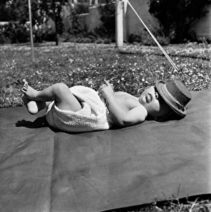Baby having a sleep on a rug wearing nappy and hat. June 1950 O24582 Baby having a sleep on a rug wearing nappy and hat. June 1950 O24582