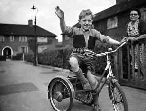 A boy plays on his tricycle on a council estate as his mother looks on 1955 A boy plays on his tricycle on a council estate as his mother looks on 1955