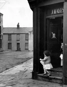 Cardiff - Old - A young child leaves a typical Cardiff corner shop in Butetown Cardiff - Old - A young child leaves a typical Cardiff corner shop in Butetown