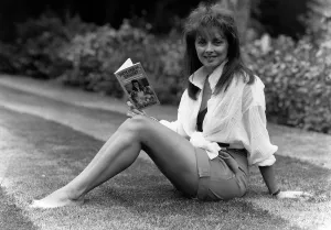 Carol Vorderman TV Presenter sitting on grass lawn holding paperback book Carol Vorderman TV Presenter sitting on grass lawn holding paperback book