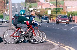 Two children on their bikes trying to cross a busy road Two children on their bikes trying to cross a busy road