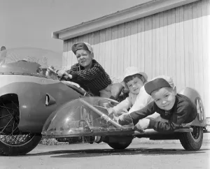 Three children Brian, Carole Ann and Colin Digby sitting on their dad' Three children Brian, Carole Ann and Colin Digby sitting on their dad'