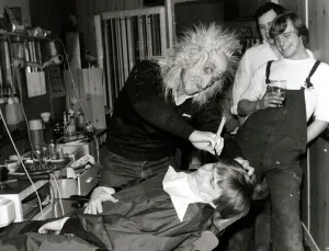 A customer sits in the barbers chair having his faced shaved by a man in a mask at Steve A customer sits in the barbers chair having his faced shaved by a man in a mask at Steve