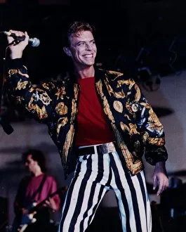 David Bowie singer on stage mike in hand wearing black and white striped trousers red David Bowie singer on stage mike in hand wearing black and white striped trousers red