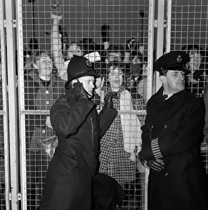 Excited female Beatles fans deafen a young policeman keeping them at bay before Excited female Beatles fans deafen a young policeman keeping them at bay before