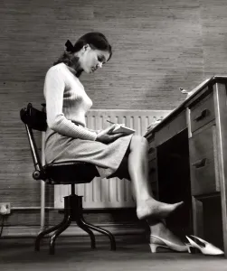 Female office worker sitting taking notes. Writing barefoot / taking shoe Female office worker sitting taking notes. Writing barefoot / taking shoe