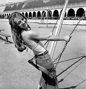 Glamour model wearing a striped vest top and a pair of jeans as she poses on a swing in a Glamour model wearing a striped vest top and a pair of jeans as she poses on a swing in a