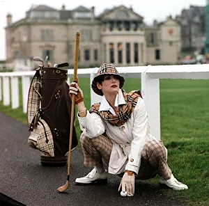 Golf Fashion woman crouching down next to golf bag clubs Burberry type checked hat Golf Fashion woman crouching down next to golf bag clubs Burberry type checked hat
