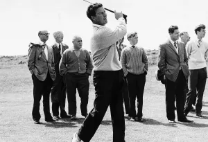 Golfer Peter Thomson playing from the fairway to the 13th hole in front of small group of Golfer Peter Thomson playing from the fairway to the 13th hole in front of small group of