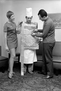 Humour. Man and woman covering a man in a Chef's uniform in plastic hearts Humour. Man and woman covering a man in a Chef's uniform in plastic hearts