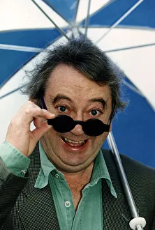 Ian McCaskill Peering over the rim of a pair of sunglasses holding umbrella C/photo Ian McCaskill Peering over the rim of a pair of sunglasses holding umbrella C/photo