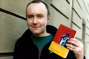 Irvine Welsh author wearing blue fleece jacket green T shirt holding copy of his book Irvine Welsh author wearing blue fleece jacket green T shirt holding copy of his book