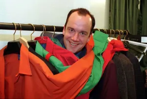 Jack Docherty TV Presenter in between clothes rail full of coloured jackets Jack Docherty TV Presenter in between clothes rail full of coloured jackets
