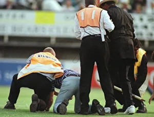 John Holder umpire is helped by steward after he was knocked to the ground by a fan at John Holder umpire is helped by steward after he was knocked to the ground by a fan at