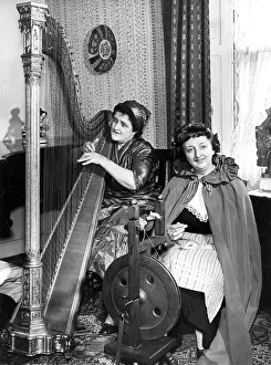 One lady playing the harp while her friend is spinning in April 1960 One lady playing the harp while her friend is spinning in April 1960
