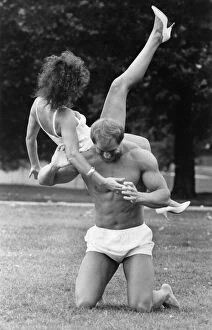 Images Dated 28th August 1986: Linda Lusardi being lifted by a muscley nearly naked Julien Mess in the park