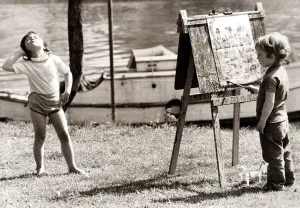 Little girl is posing whilst the young painter gets to work. Circa 1960 Little girl is posing whilst the young painter gets to work. Circa 1960
