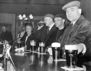 Locals and regulars standing at the bar, drinking in the one time Locals and regulars standing at the bar, drinking in the one time