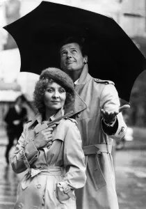 Lulu holding a Dunhill gun and Roger Moore together in the rain outside the Hilton Hotel Lulu holding a Dunhill gun and Roger Moore together in the rain outside the Hilton Hotel