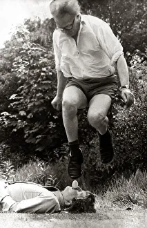 A man leaping over man's face holding an egg in mouth January 1974 A man leaping over man's face holding an egg in mouth January 1974