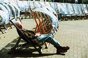 Man sleeping on deckchair in a London park on windy day Man sleeping on deckchair in a London park on windy day