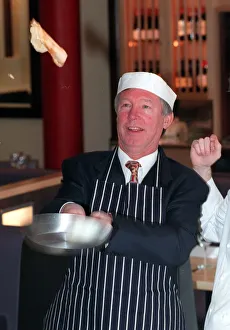 Manchester United manager Alex Ferguson shows how its done on Shrove Tuesday as tosses a Manchester United manager Alex Ferguson shows how its done on Shrove Tuesday as tosses a