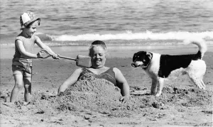 00055 Prints: Vera Tomlinson gets buried in the sand by little Kate Argent Print