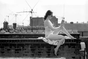 Retro Swimwear Fashion Prints: A model wearing a bikini reading a book as she sunbathes on a rooftop on Kings Road in