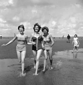 Retro Swimwear Fashion Prints: Girls in swimsuits running on the beach at Blackpool. 5th August 1958