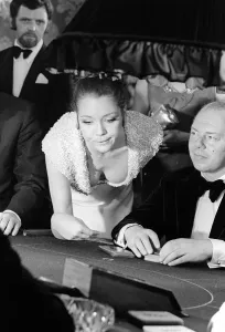 Prints of Diana Rigg in a low cut dress leans across the Black Jack table in a casino showing off her cleavage James Bond 007 film On Her Majestys Secret Service March 1969 0100to0199 Prints: Diana Rigg in Low-Cut Dress, On Her Majesty's Secret Service Print (1969)
