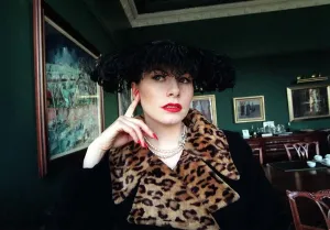 90s Fashion Model Prints: Evita Fashion Model sitting down black coat with leopard skin collar feather hat black