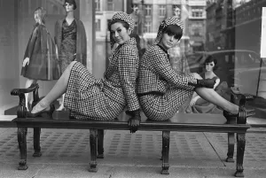 Prints of Fashions taken during London Fashion Week 1964 Two piece suit with matching hats - two models sitting on a bench back to back posing for the camera London Fashion Week Prints: London Fashion Week 1964 Two Piece Suit Print (00197)