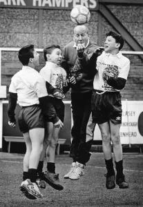 Prints of Bobby Charlton pictured training with school boys from Bebington High School, The Wirral, Liverpool, Merseyside. Left to right are Stephen Swanick, Carl Houghton and Kevin Davies, all aged 12 Merseyside Prints: Bobby Charlton with Bebington High School Boys Print 1993