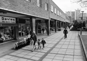 A mother and two young boys walk past the shops in Smithford Way, Coventry A mother and two young boys walk past the shops in Smithford Way, Coventry