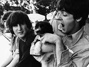 Paul McCartney of The Beatles coddles a puppy watched by John Lennon on the set of Help Paul McCartney of The Beatles coddles a puppy watched by John Lennon on the set of Help